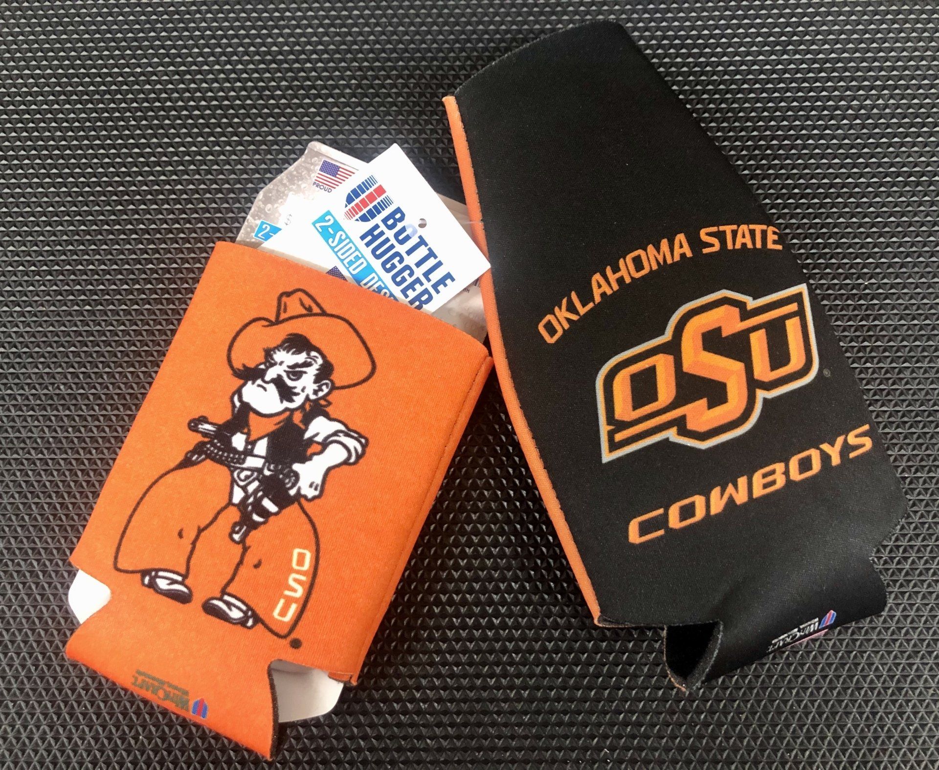 Two Oklahoma State University beverage koozies: one orange with Pistol Pete, one black with the OSU logo.
