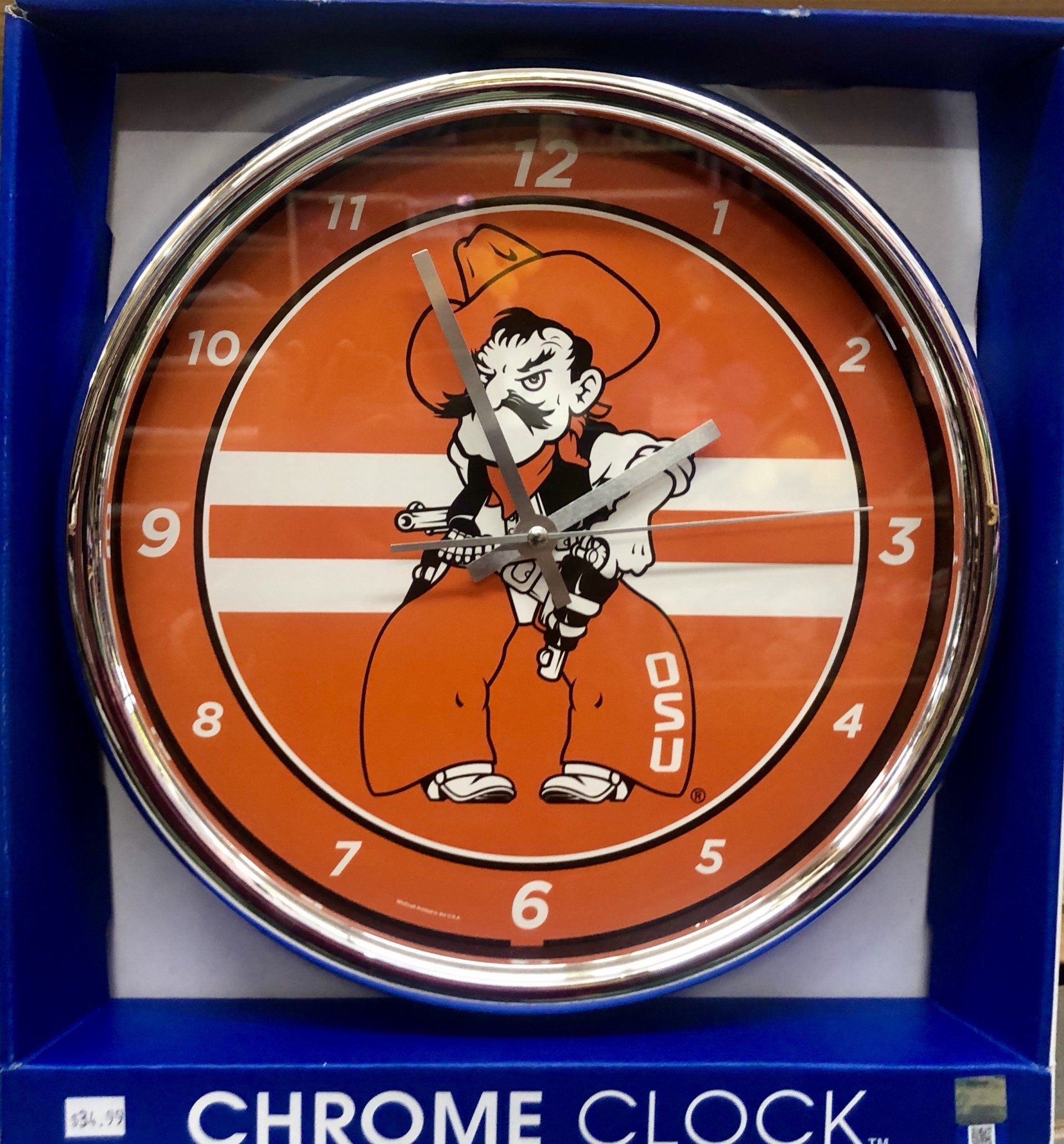 A chrome-rimmed wall clock featuring the orange Oklahoma State University Pistol Pete mascot inside its box.