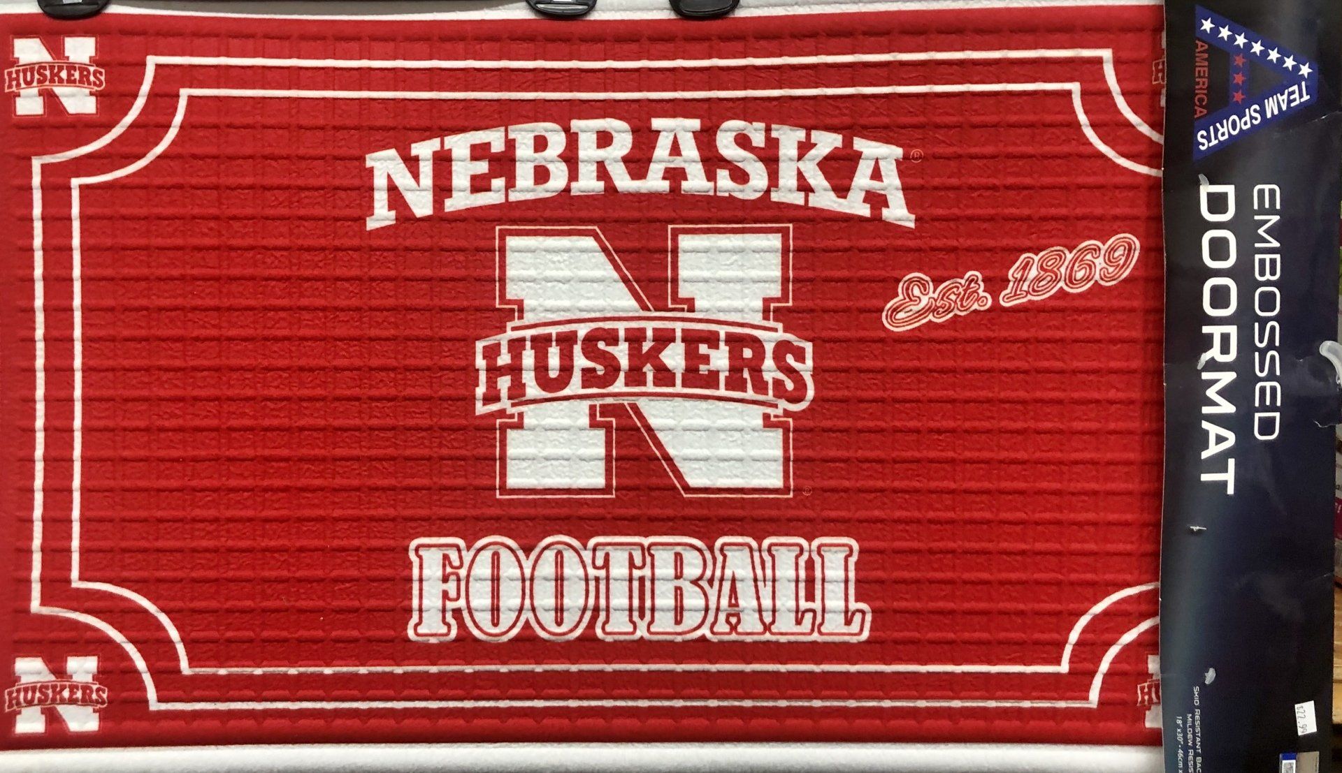 A red University of Nebraska Huskers football embossed doormat with a large white N and the text 