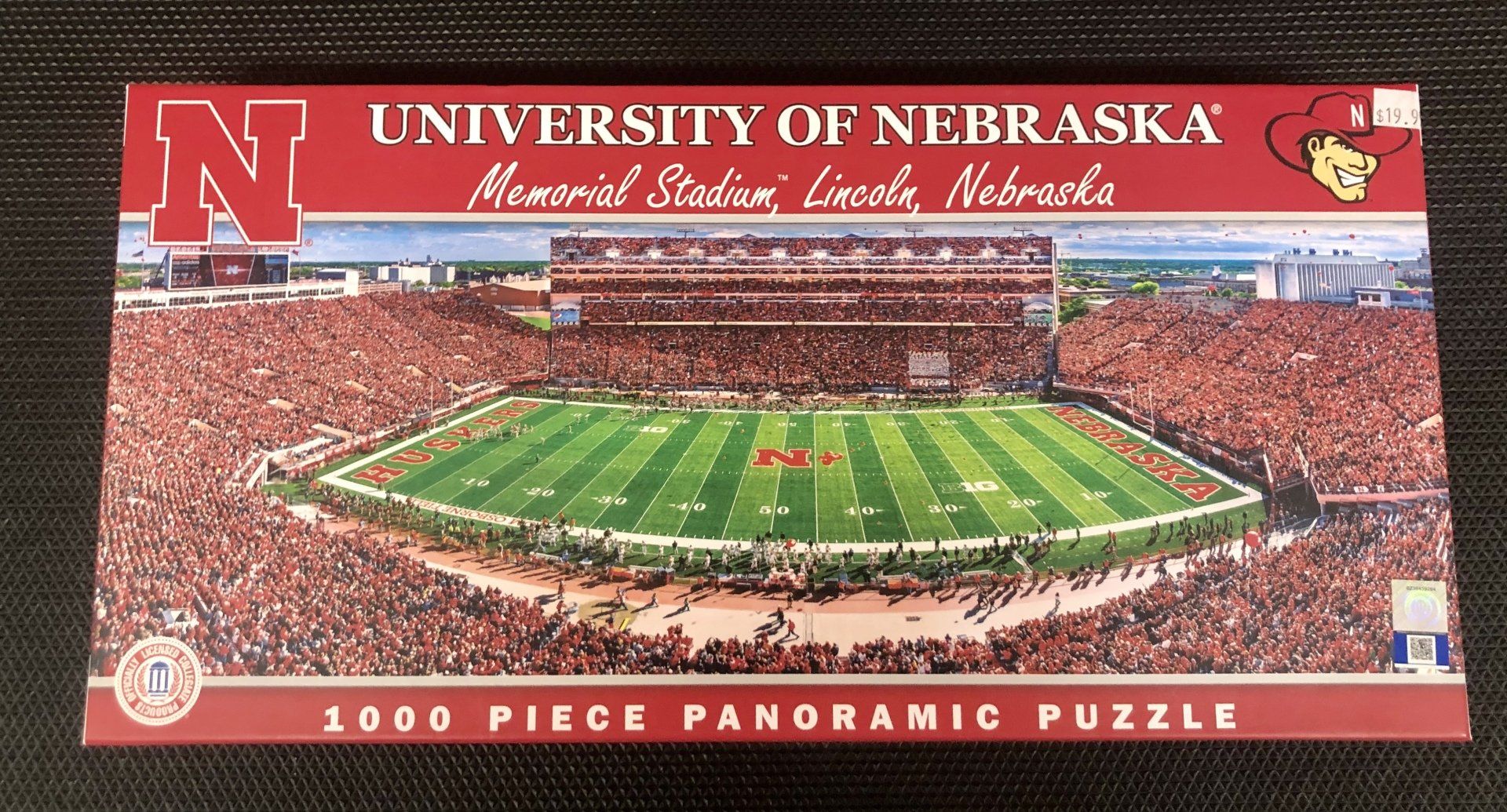 A 1000-piece panoramic jigsaw puzzle box featuring an aerial view of Memorial Stadium at the University of Nebraska.