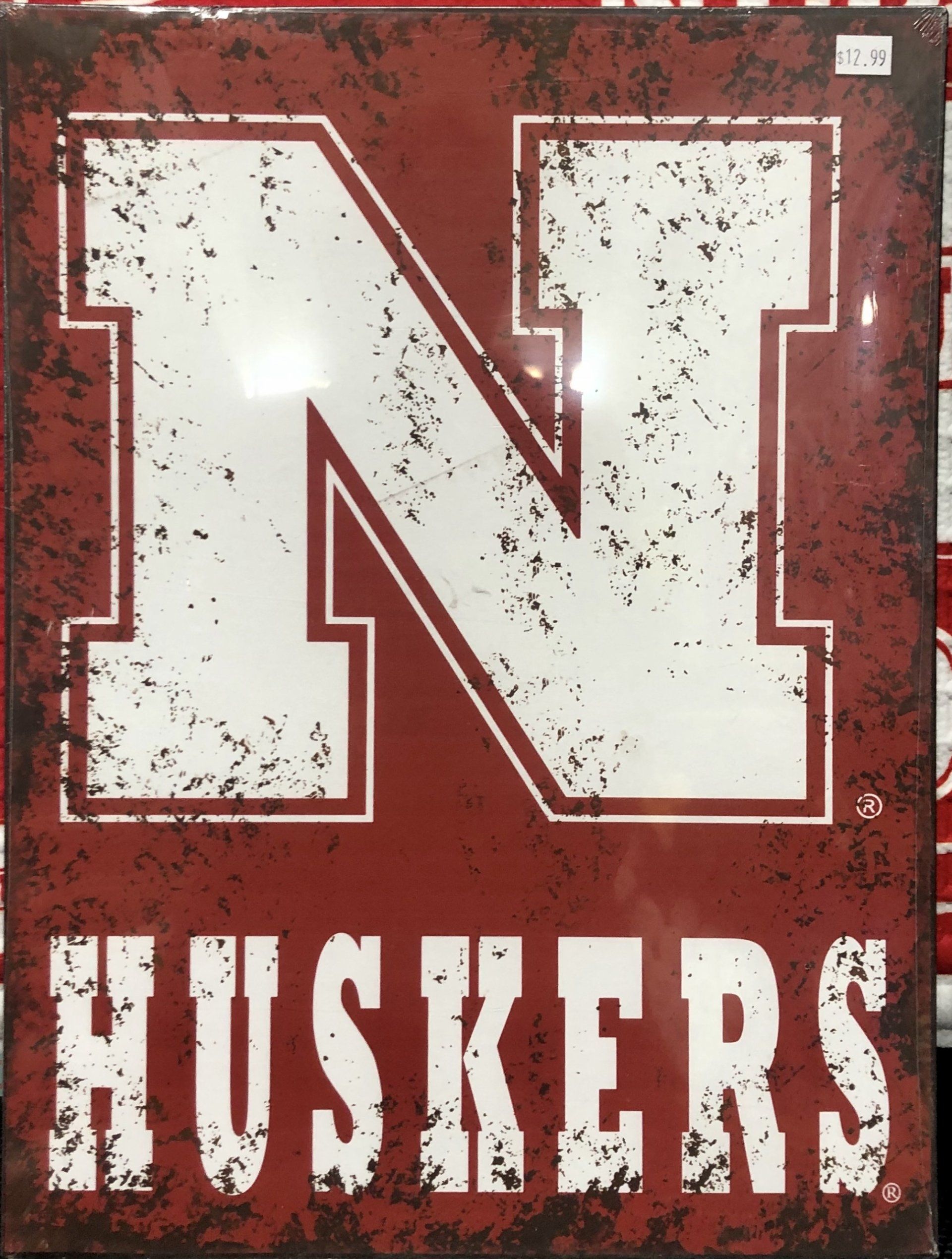 A rectangular metal sign featuring the white Nebraska 