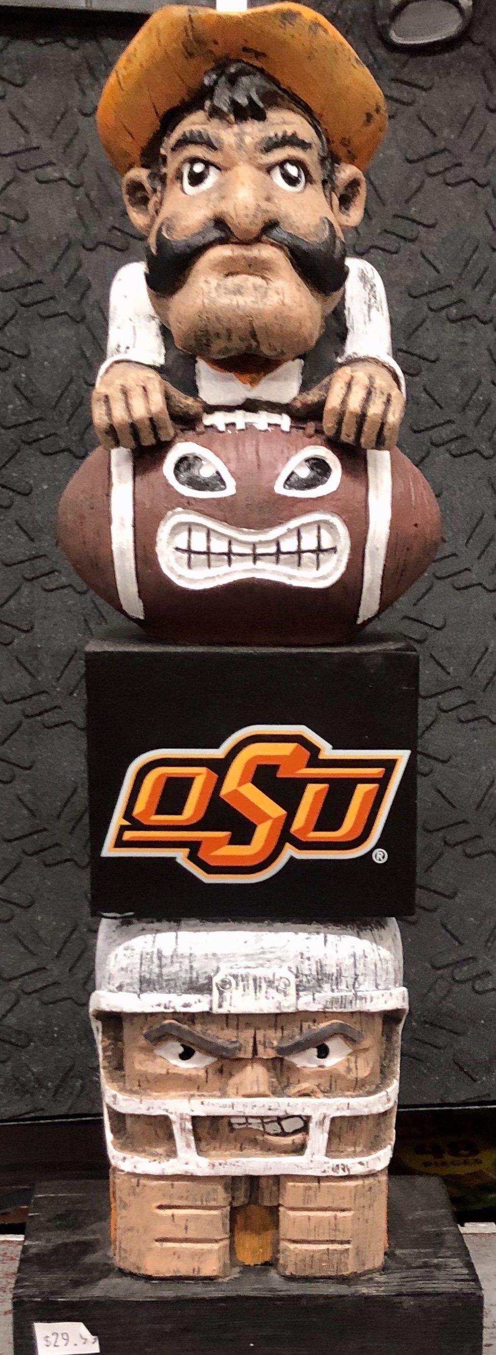 A wooden totem pole featuring a cowboy mascot over an OSU logo and a football player wearing a helmet.