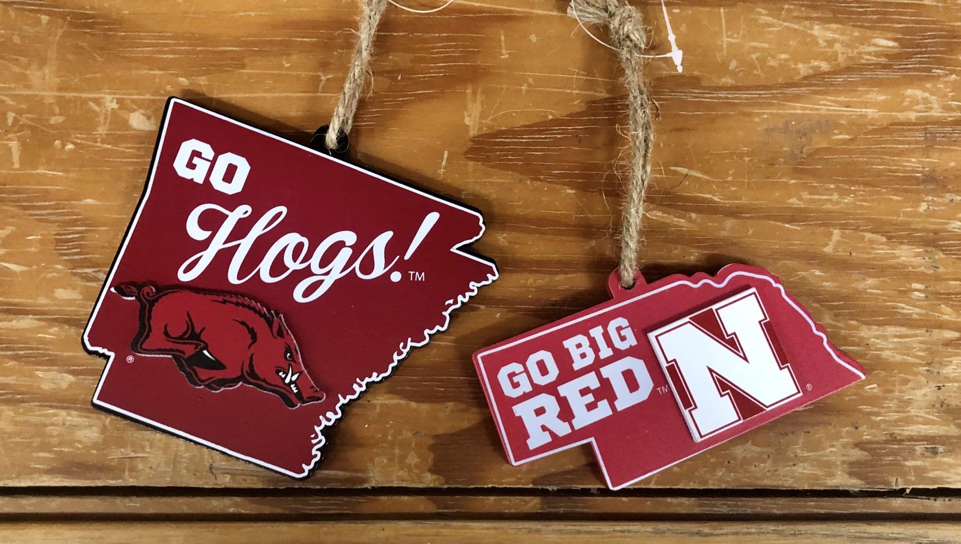 Two wooden state-shaped ornaments on a wood background: Arkansas (