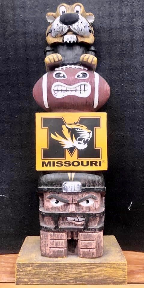 A University of Missouri Tigers themed wooden-style totem pole with a mascot, football, logo block, and helmeted player.