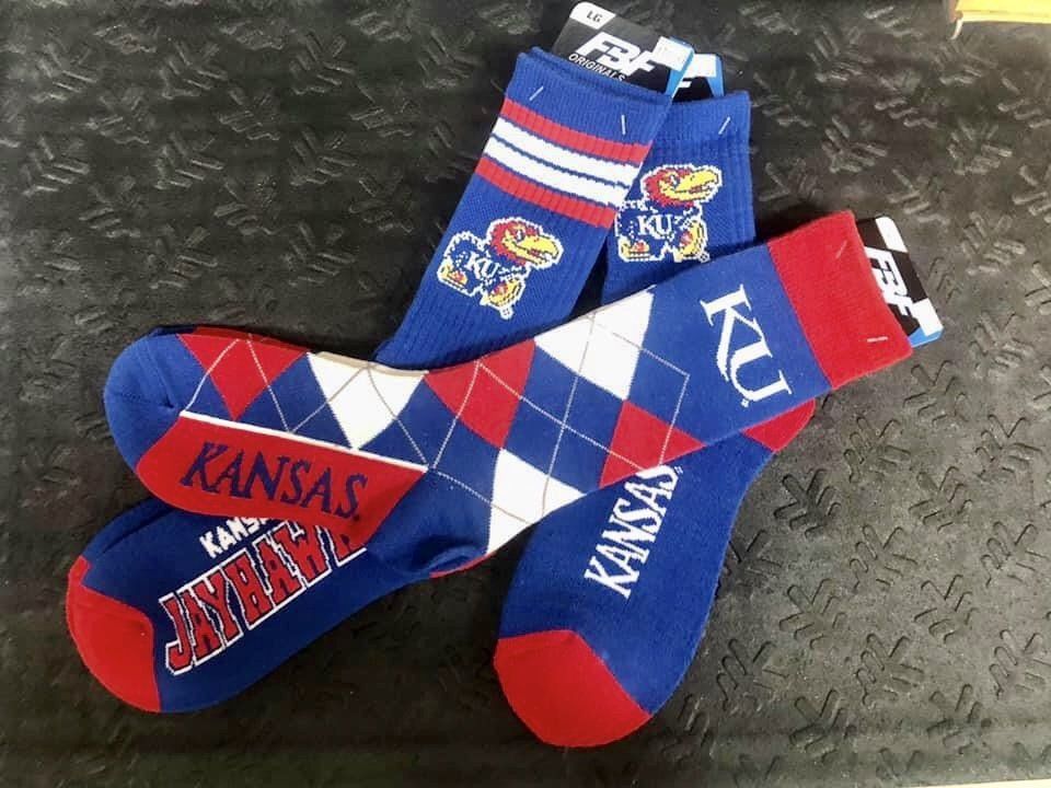 Two pairs of Kansas Jayhawks-themed socks, one argyle with the KU logo and the other with striped cuffs and team mascots.