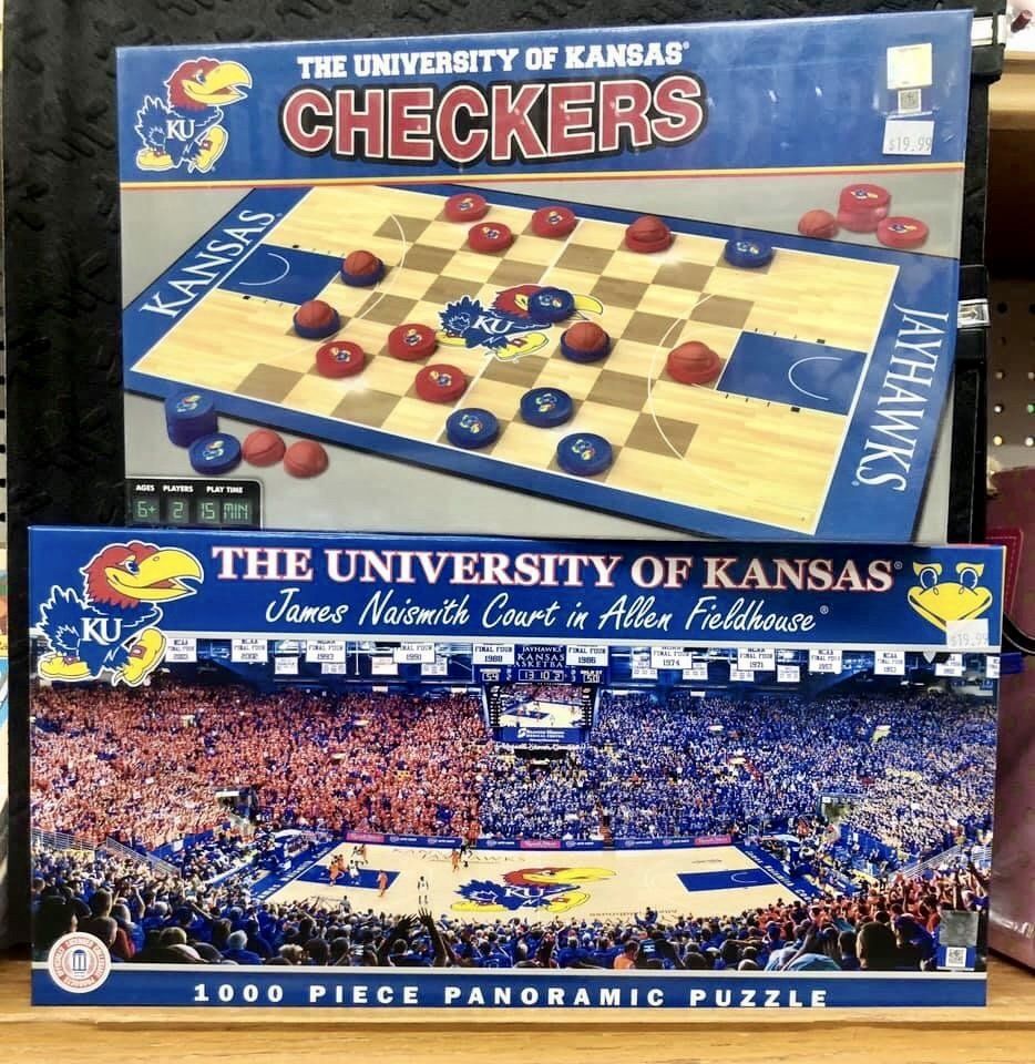 University of Kansas Checkers game box sitting atop a 1000-piece James Naismith Court panoramic jigsaw puzzle box.