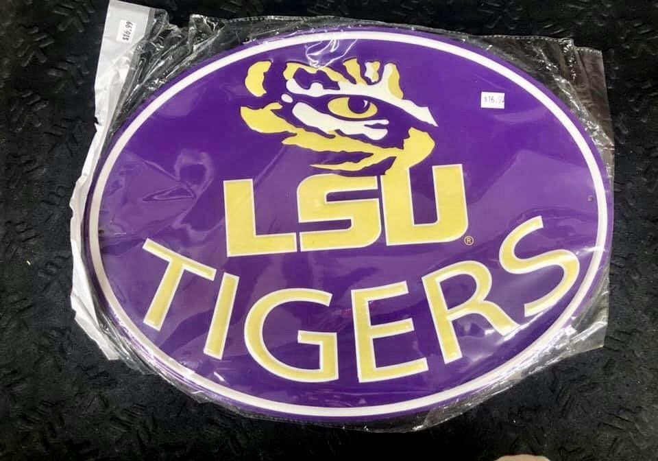 An oval, purple and gold Louisiana State University Tigers sign, sealed in clear plastic packaging.