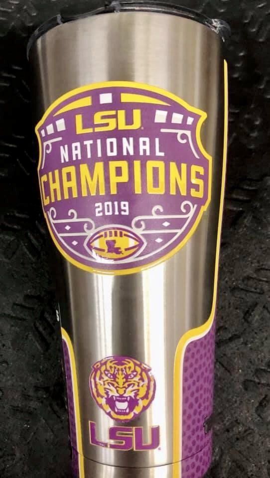 A stainless steel tumbler featuring an LSU 2019 National Champions logo, a tiger mascot, and purple and gold accents.