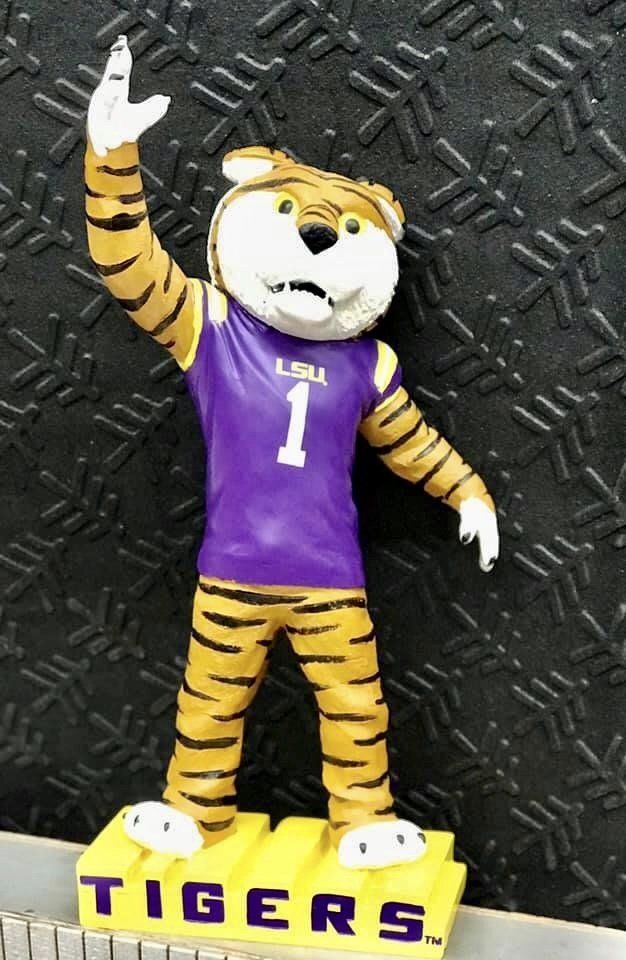 A Mike the Tiger mascot figure in a purple LSU jersey, standing on a yellow base labeled 