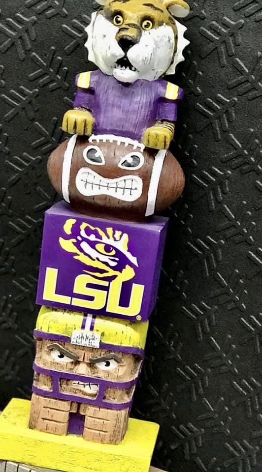 A vertical LSU-themed wood carving featuring a tiger mascot, a football, the team logo, and a helmeted player head.