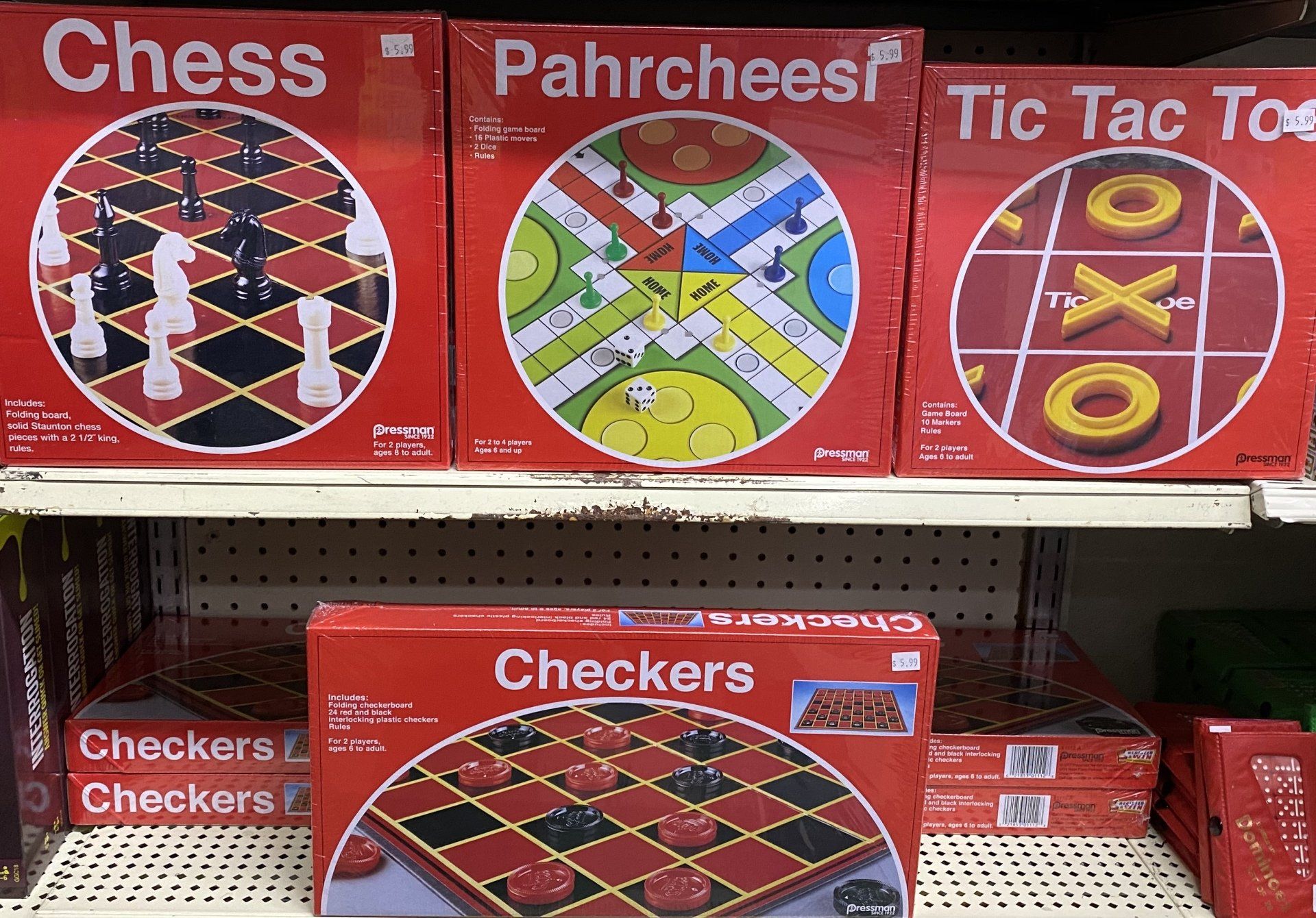 A store shelf displaying red boxes of classic board games, including Chess, Parcheesi, Tic Tac Toe, and Checkers.