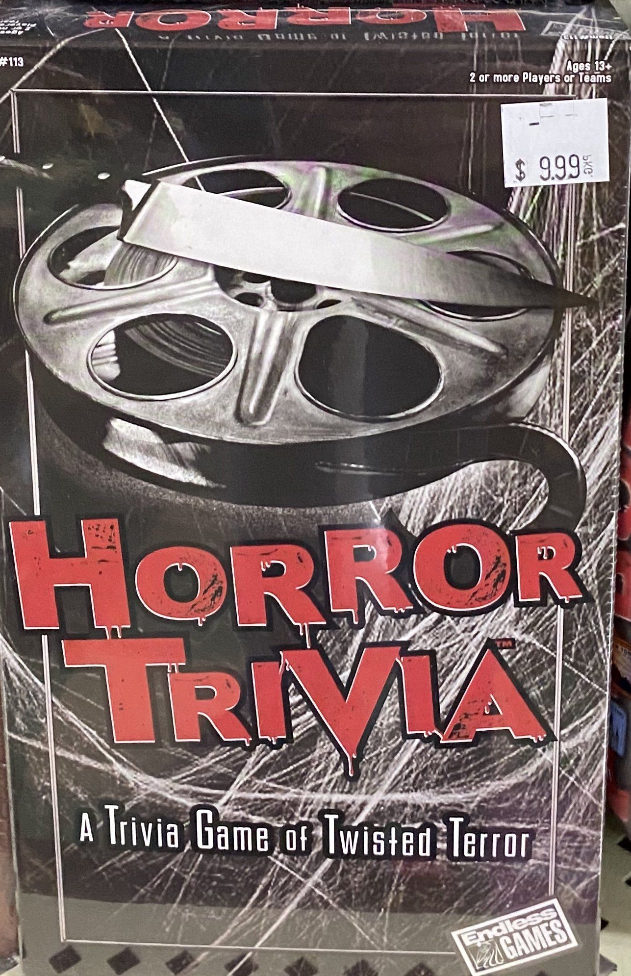 Horror Trivia board game box. A film reel sliced by a knife, red text, and a price tag on a dark, scratched background.