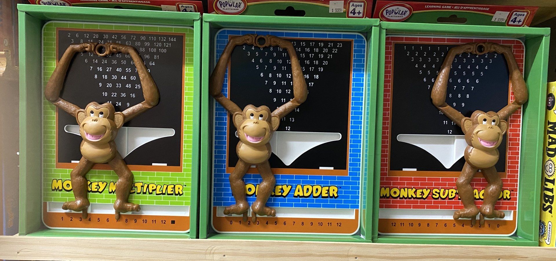 Three toy monkeys in green, blue, and red boxes labeled 