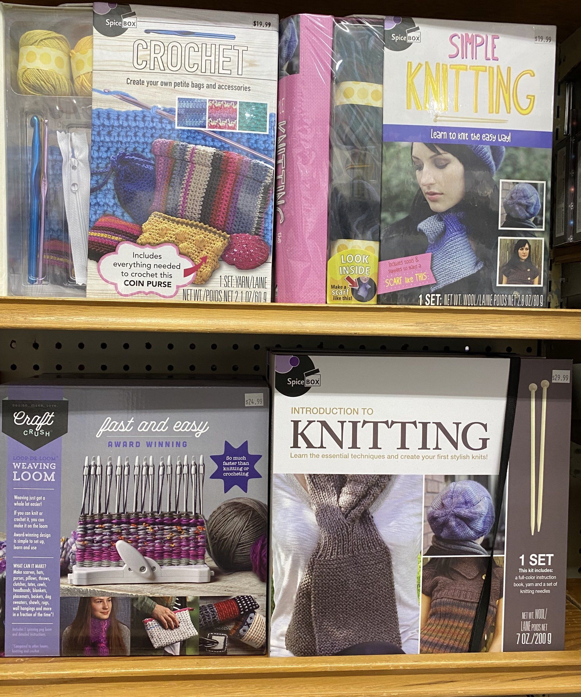 Two shelves displaying various DIY craft kits for knitting and crochet on a pegboard wall.