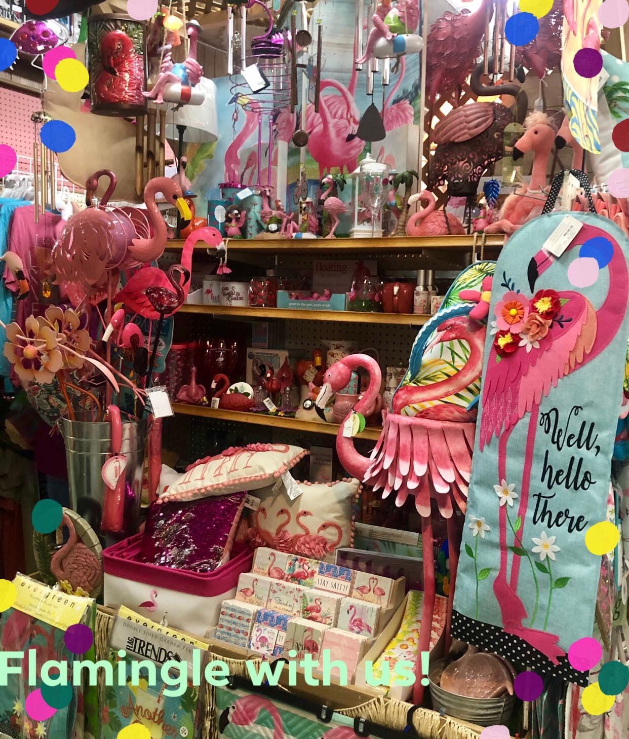 A colorful retail display filled with pink flamingo-themed decor, including figurines, ornaments, and a decorative banner.