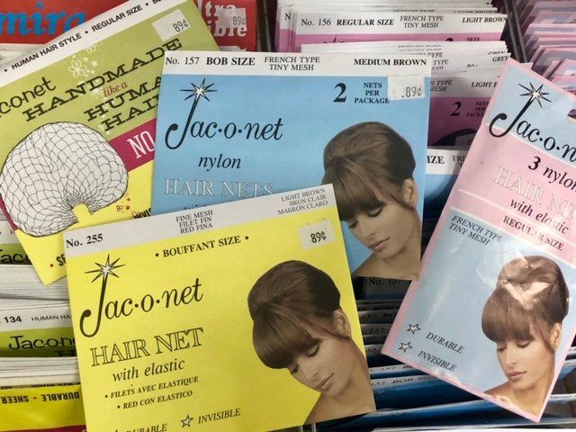 Several packs of Jac-o-net hair nets in yellow, blue, and pink, each featuring a photo of a styled hairstyle.