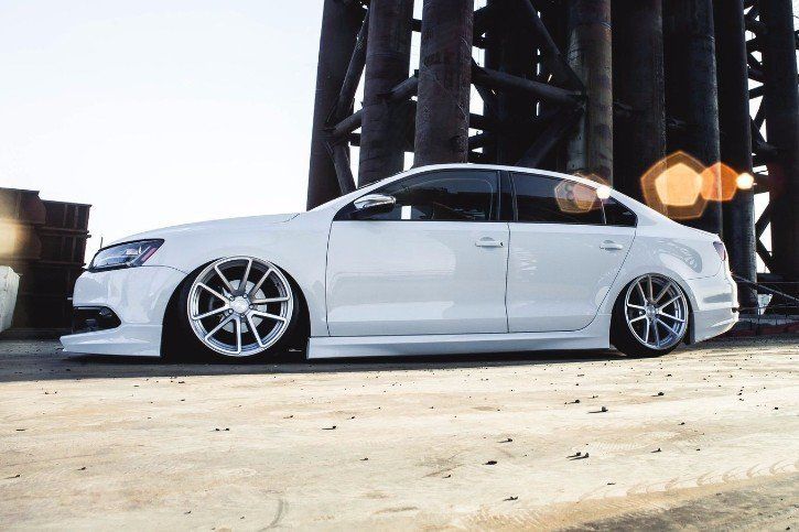 A white car is parked on the side of the road under a bridge.