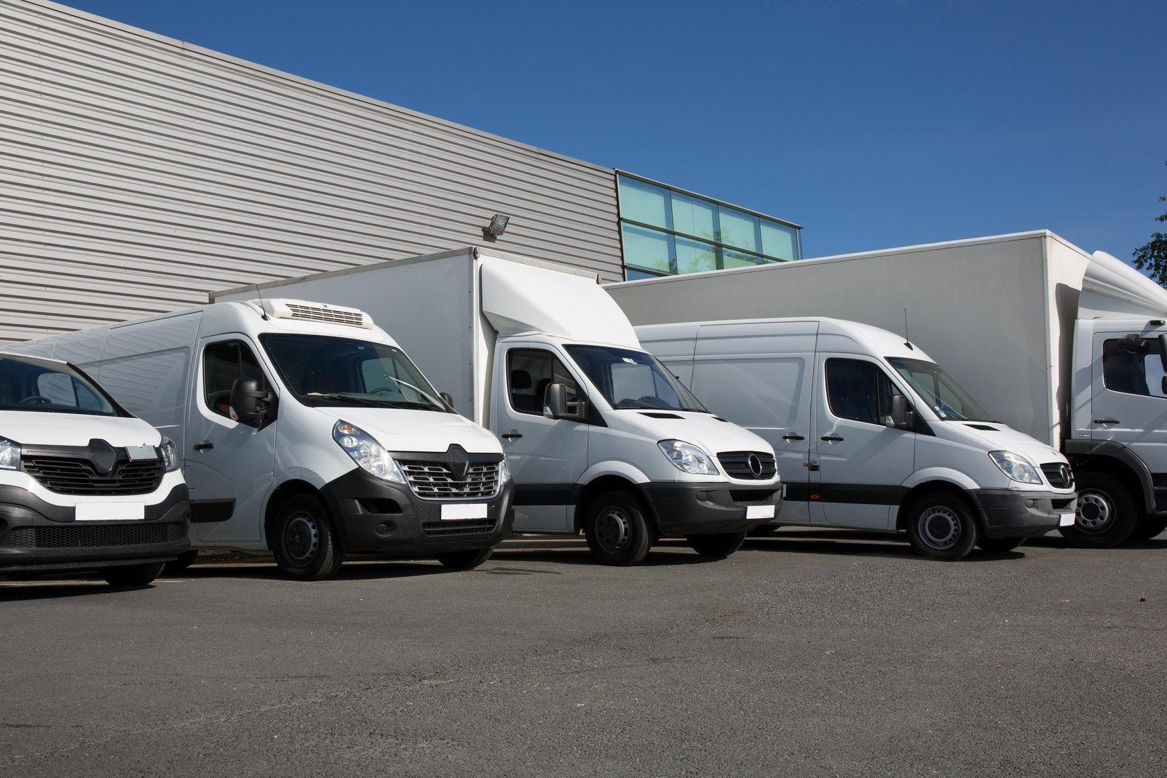A row of white vans parked in front of a building.
