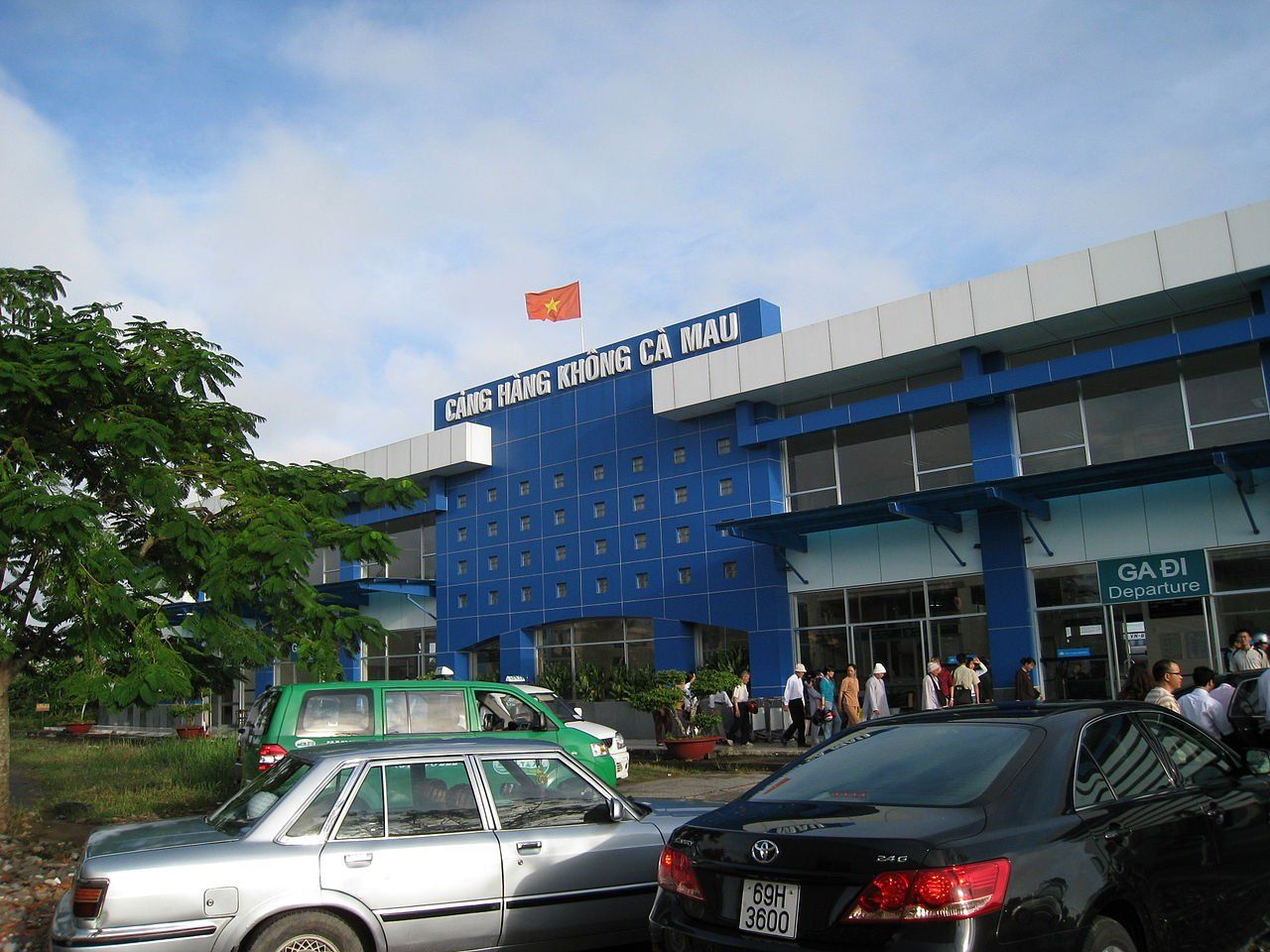 Cars are parked in front of a blue building with a flag on top