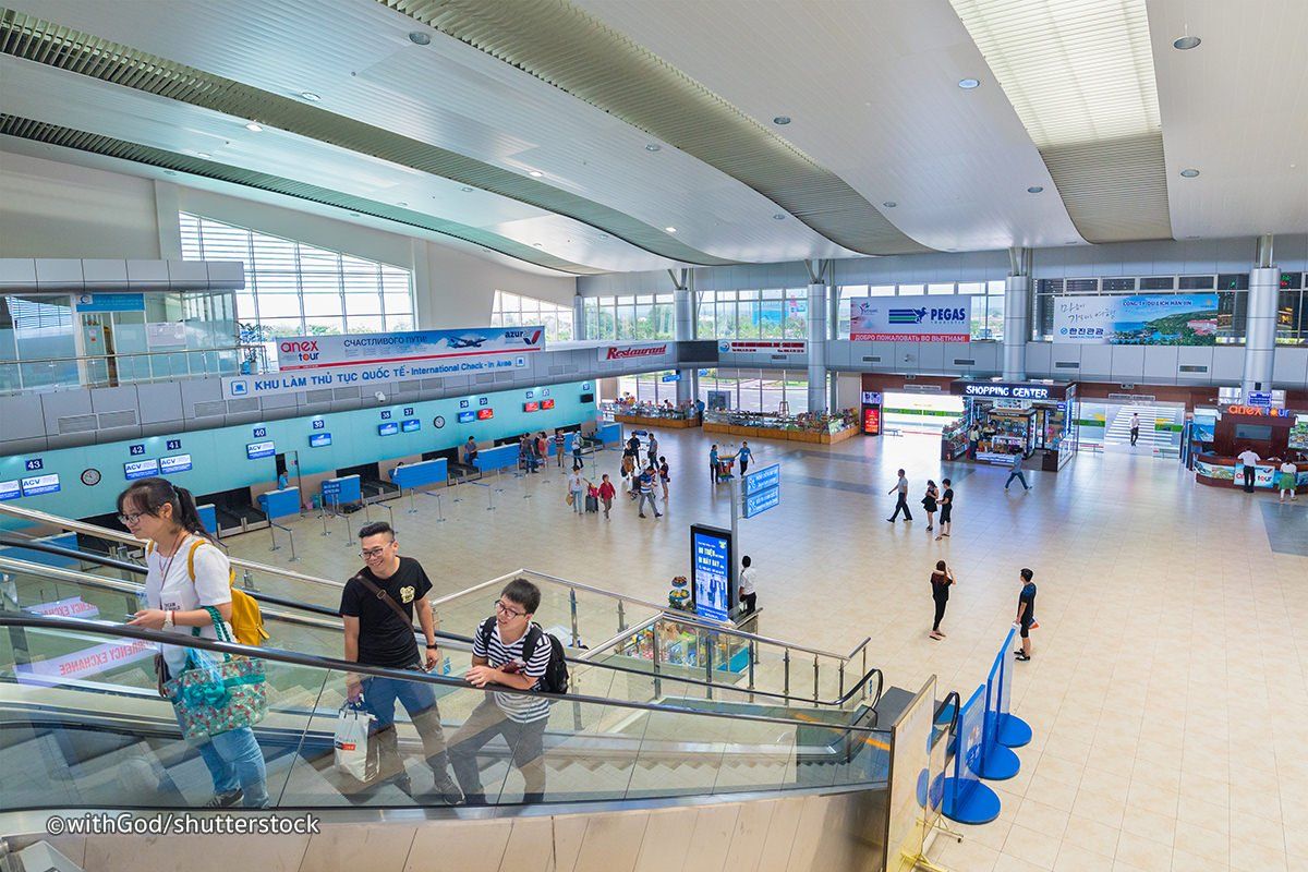 A group of people are walking down escalators in an airport.
