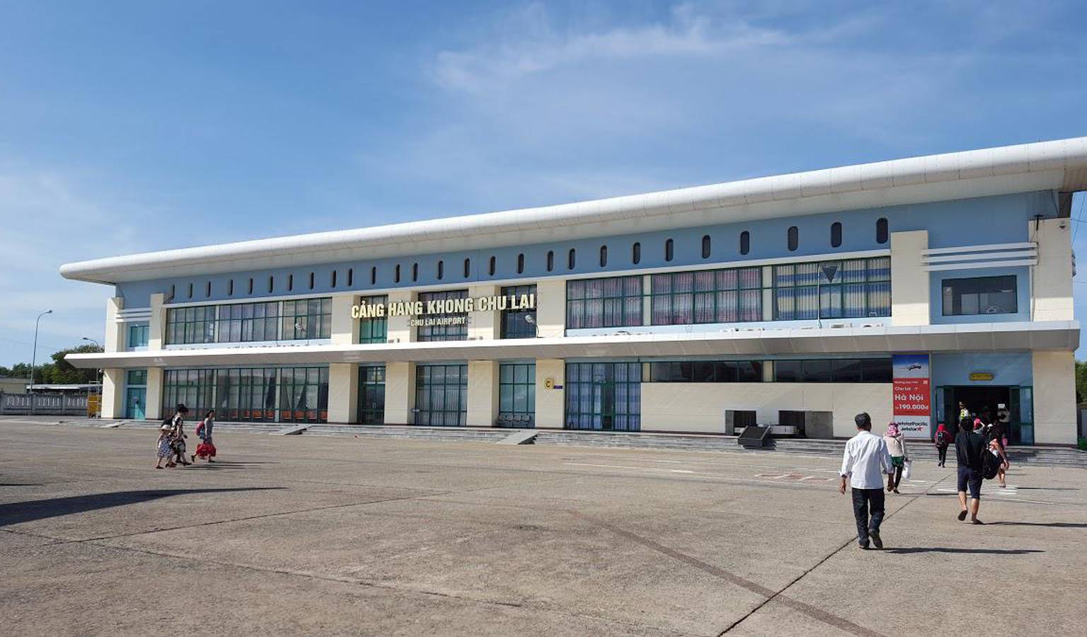 A large building with a lot of windows and people walking in front of it