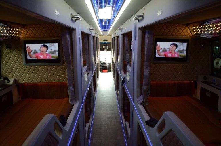 The inside of a bus with two televisions on the wall