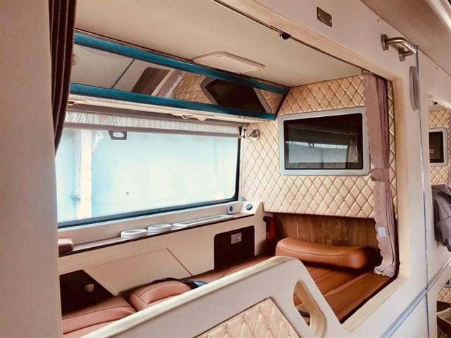 The inside of a bus with a couch and a television.
