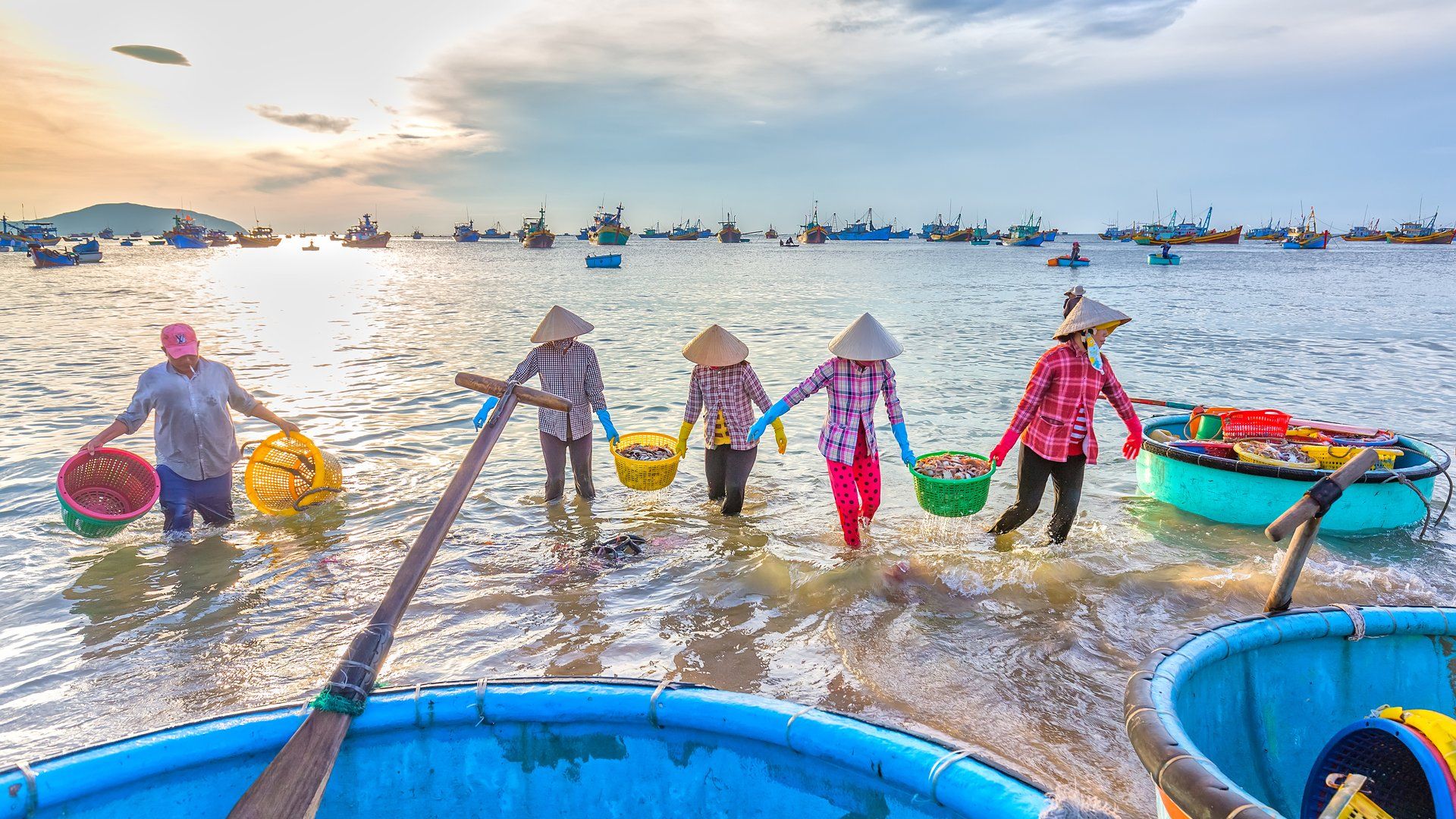 A group of people are standing in the water carrying baskets.