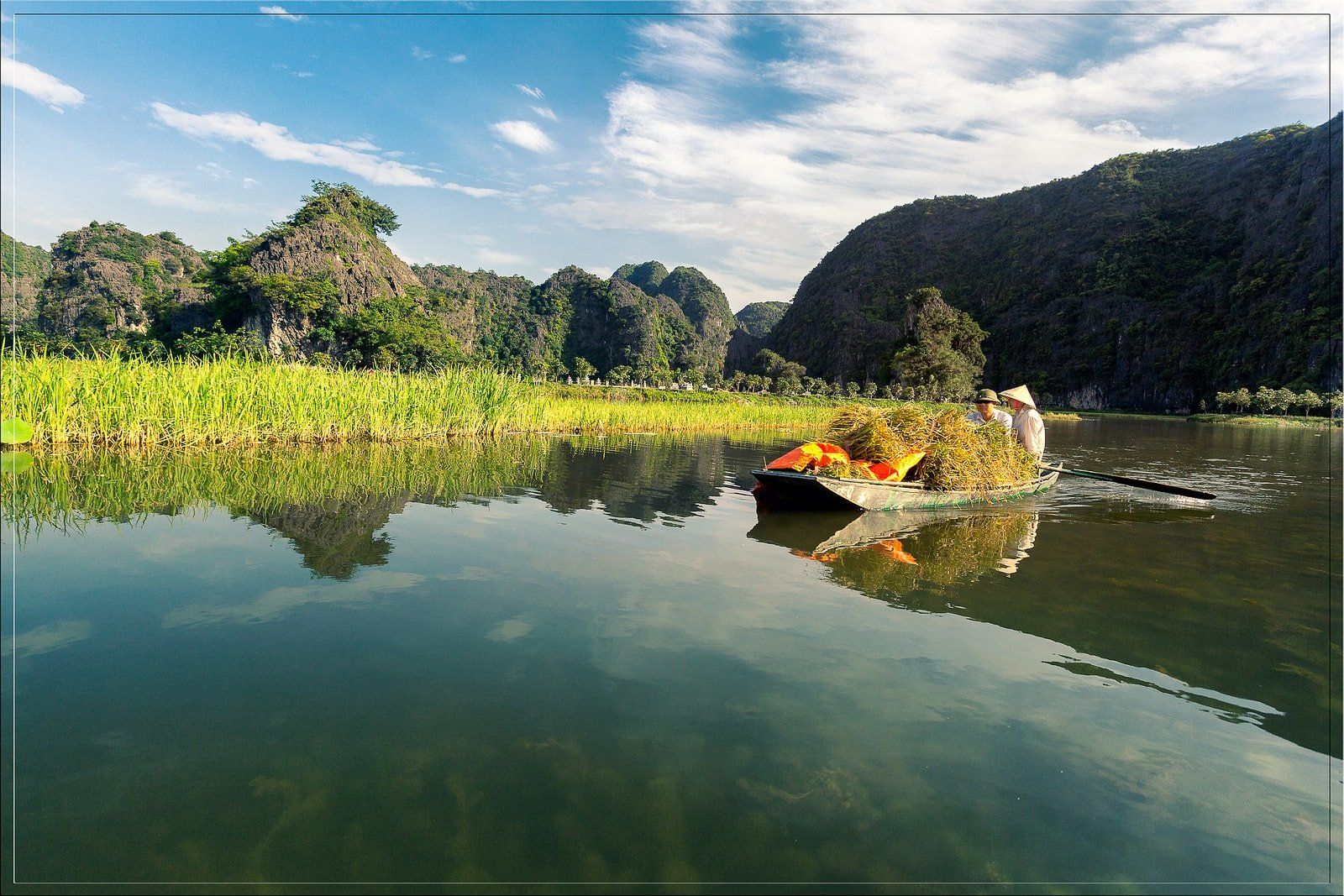 A man is rowing a boat on a lake with mountains in the background.