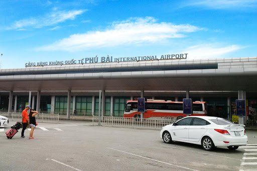A white car is parked in front of an airport building.