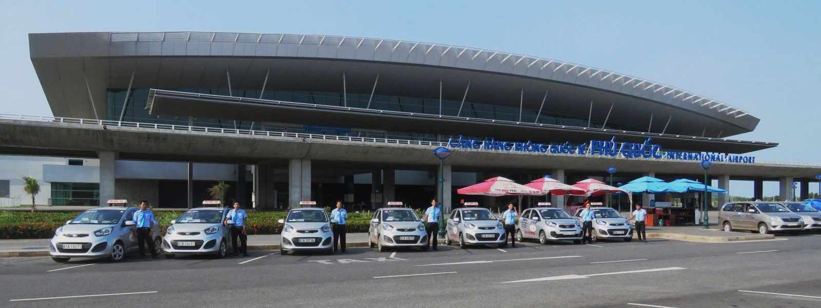 A row of cars are parked in front of a large building.