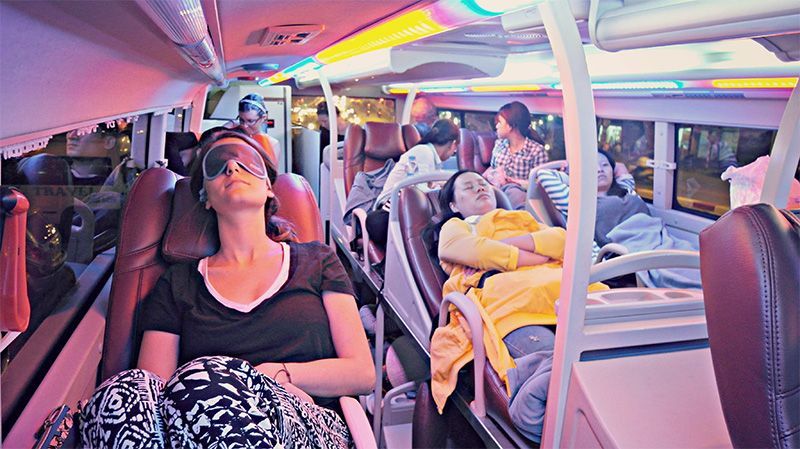 A woman is sleeping on a bus with her eyes closed.