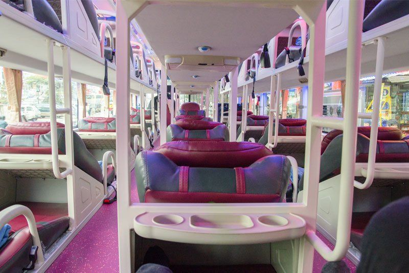 The inside of a bus with a lot of beds and tables.