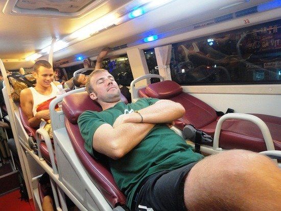 A man in a green shirt is sleeping on a bus