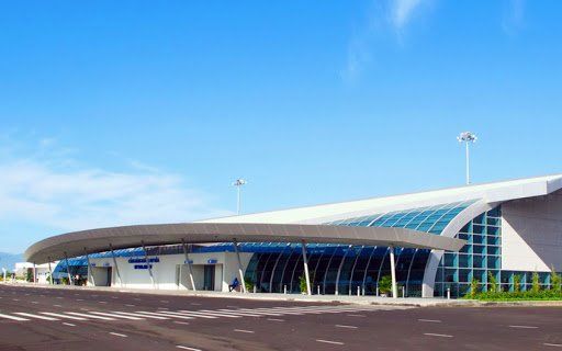 A large white building with a curved roof and a blue sky in the background.