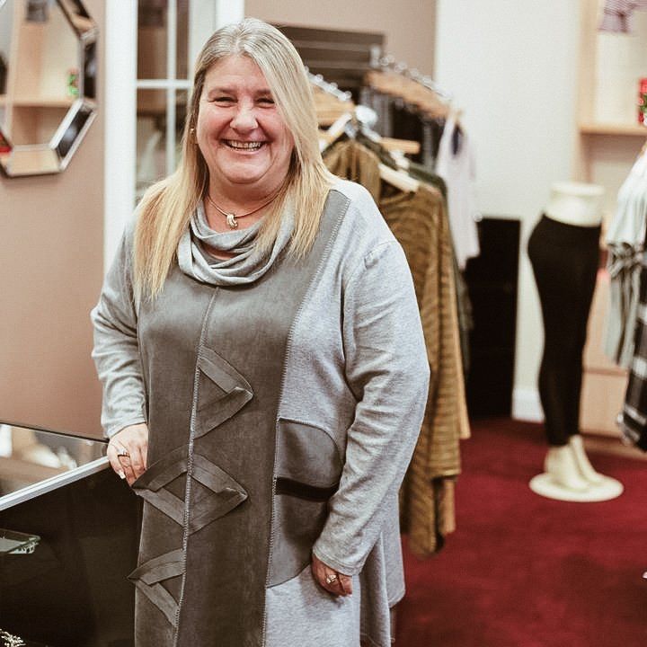 A woman in a grey dress is smiling in a store