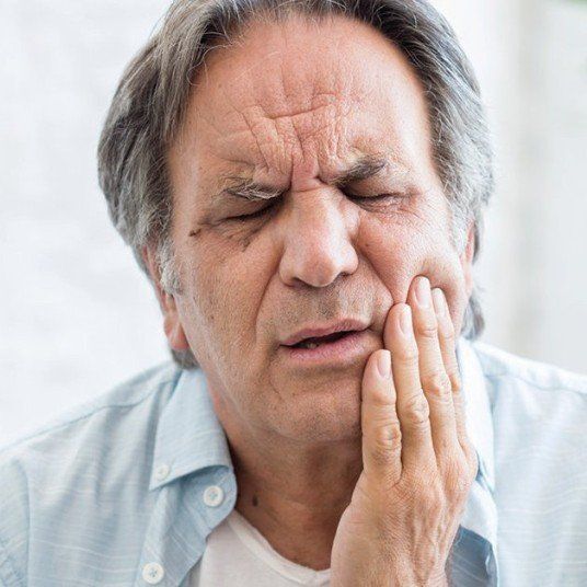 A man is holding his face in pain because of a toothache.