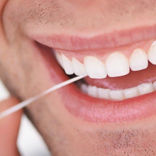 A man is flossing his teeth with dental floss