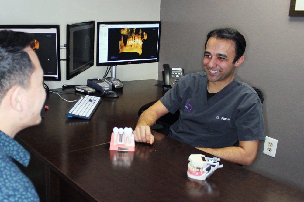Dr. Omar is sitting at a desk talking to another man