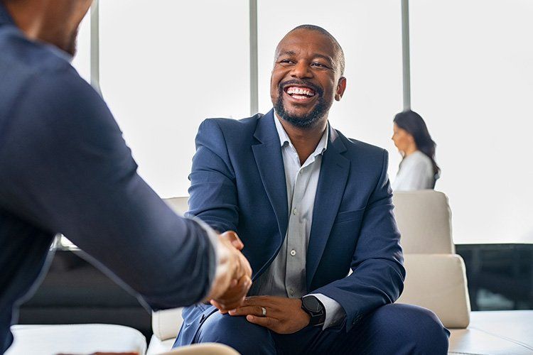 A man in a suit is shaking hands with another man in an office.