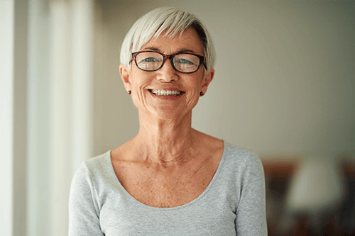 An older woman wearing glasses is smiling for the camera.