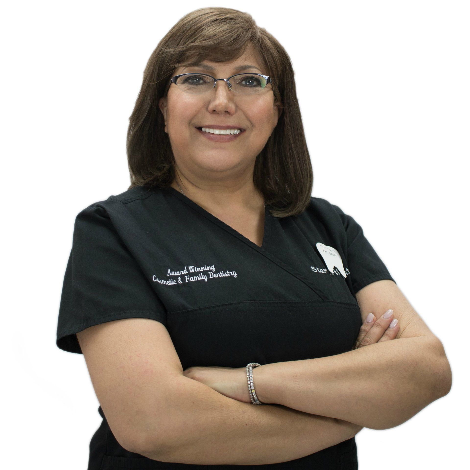 A woman wearing glasses and a black scrub top smiles with her arms crossed