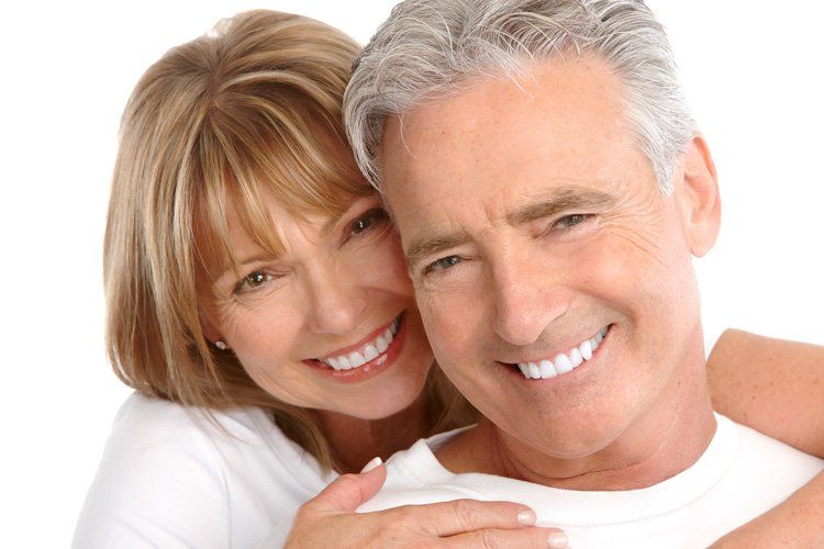A man and a woman are hugging each other and smiling for the camera.