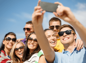 A group of young people are taking a selfie with a cell phone.