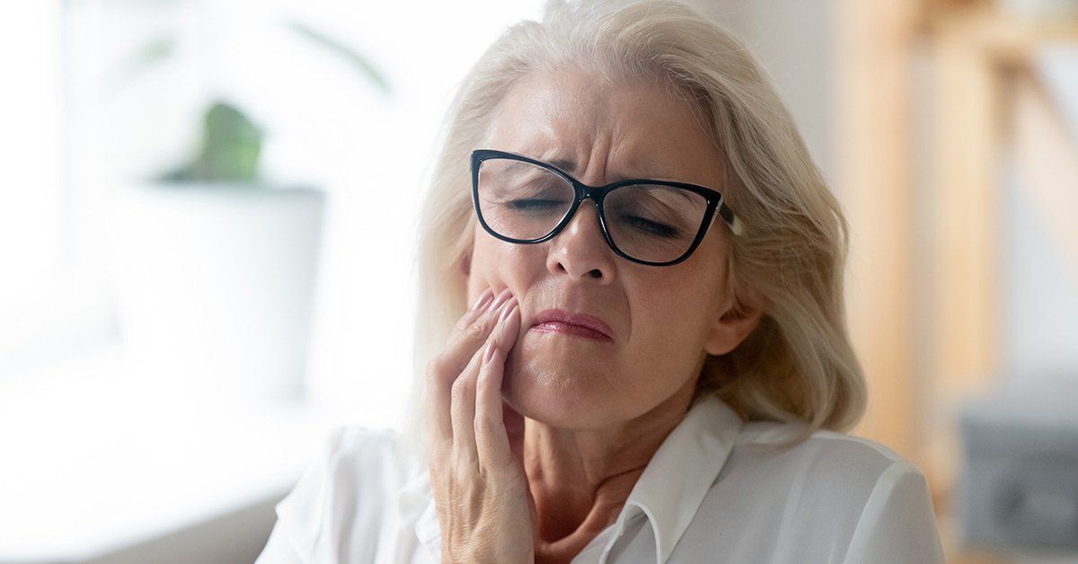 senior caucasian woman experiencing painful gum abscess symptoms and clutching cheek