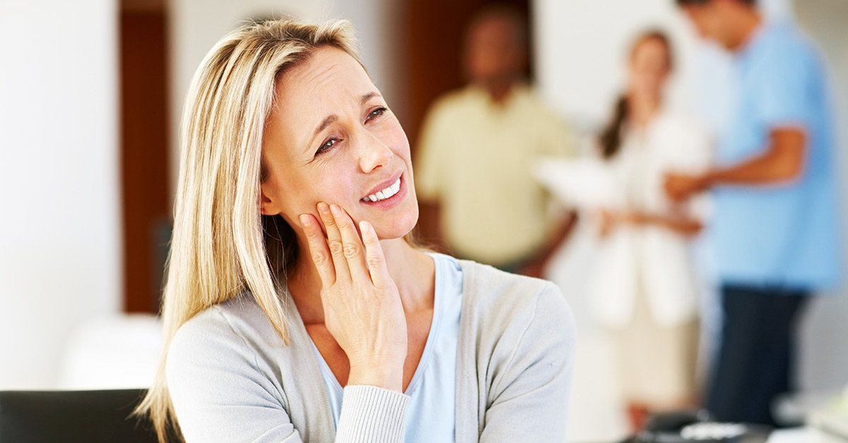 A woman with a toothache is smiling in front of a group of people