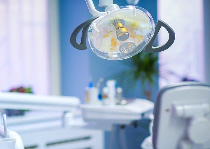 A dental office with a dental chair and a dental light hanging from the ceiling.