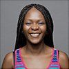 A woman with braids is smiling and wearing a pink tank top.