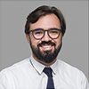 A man with a beard and glasses is wearing a white shirt and tie.