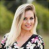 A woman in a floral dress is smiling for the camera.
